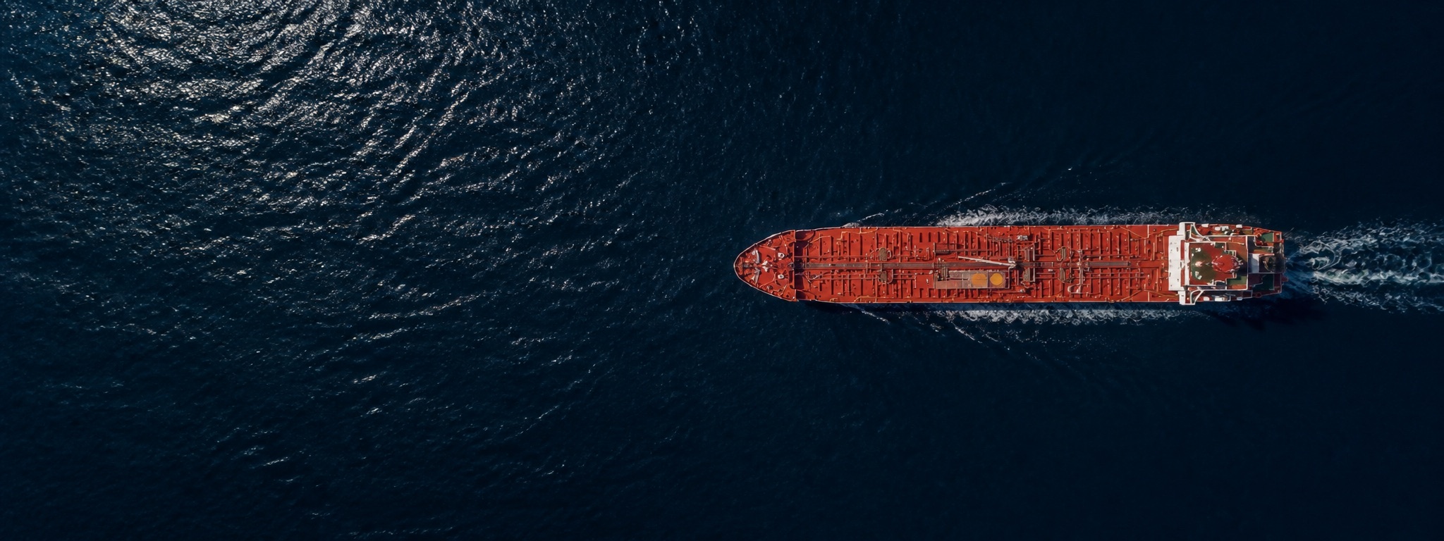 A commercial cargo vessel moving through dark blue water